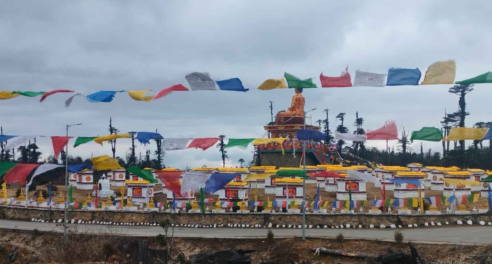 Colourful prayer flags flying over the 108 chortens and Buddha statue on the Tawang route, Arunachal Pradesh