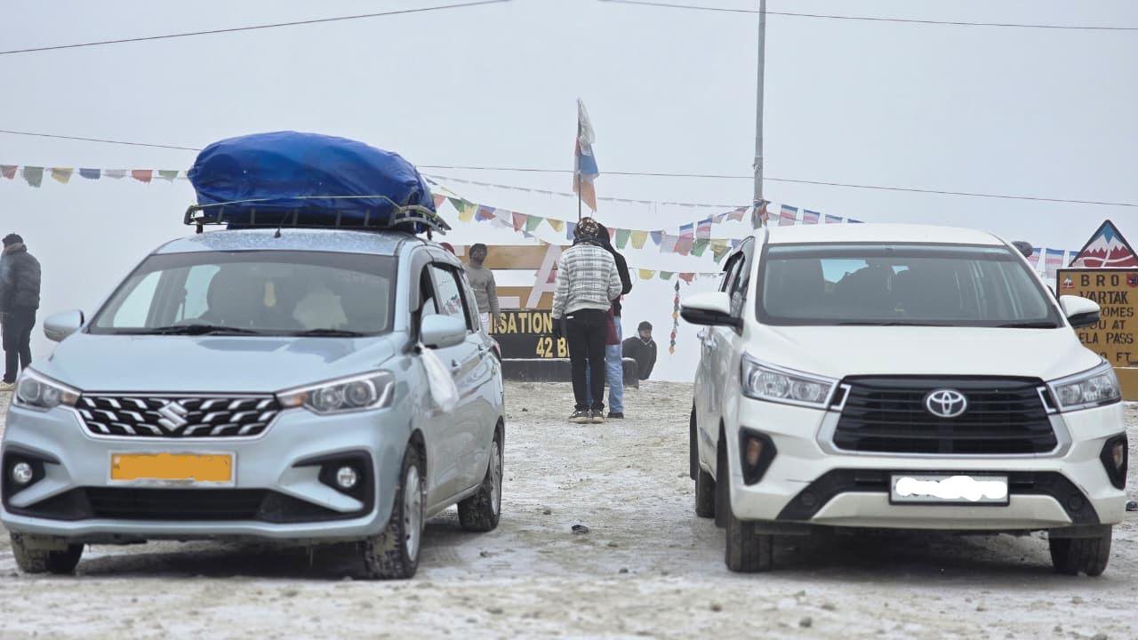 Dorjee Tours and Travels Innova Crysta and Ertiga fleet at snowy Sela Pass, Arunachal Pradesh